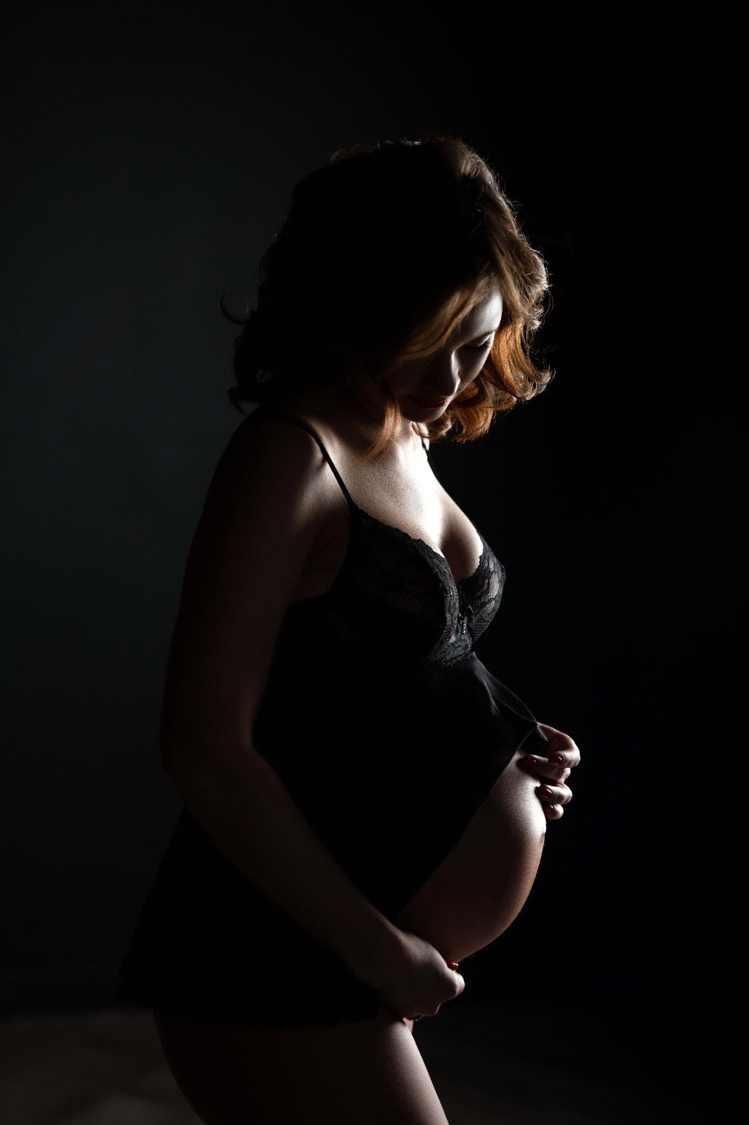 Вагітна жінка в чорній білизні, освітлені м'яким світлом