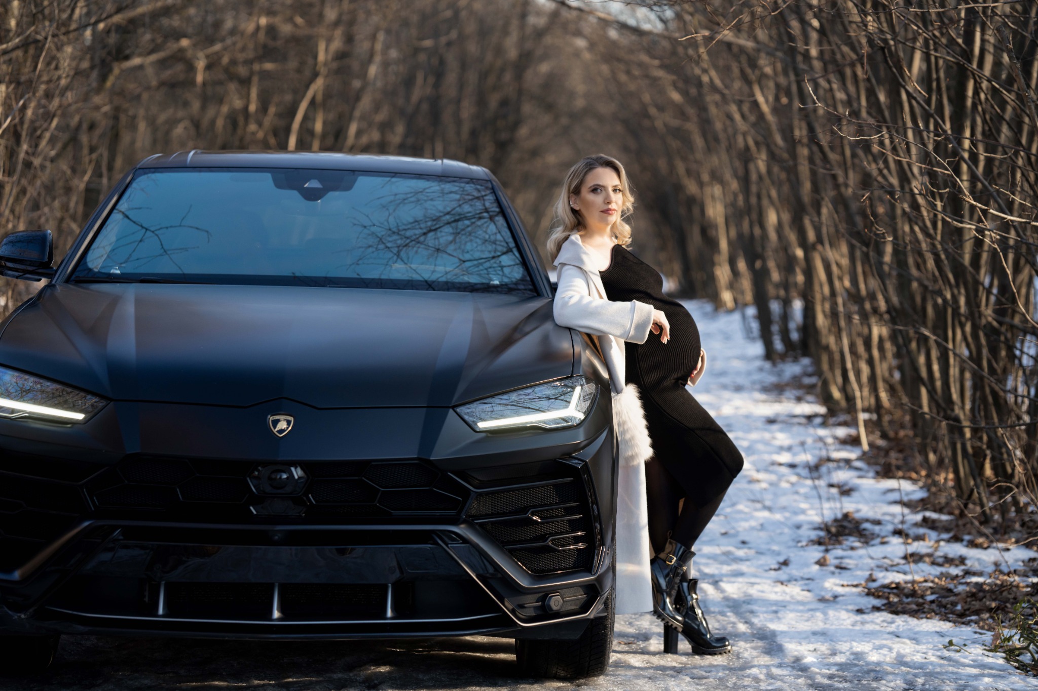 Вагітна жінка в зимовому лісі біля чорного авто