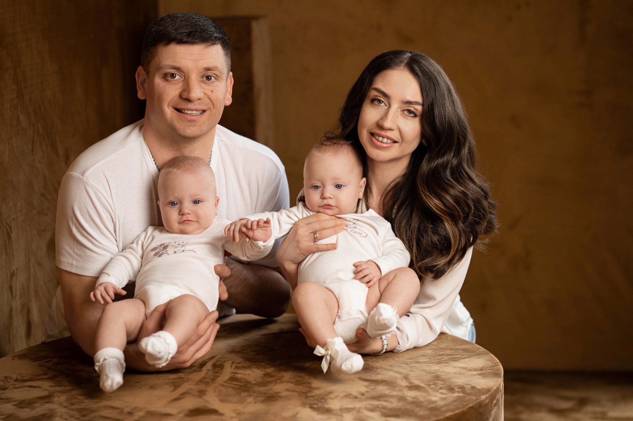 Сім'я з близнюками постановки на тлі теплого інтер'єру.