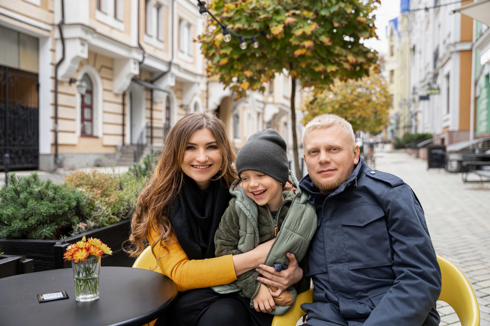 Мама, тато та син обіймаються за столиком на вулиці