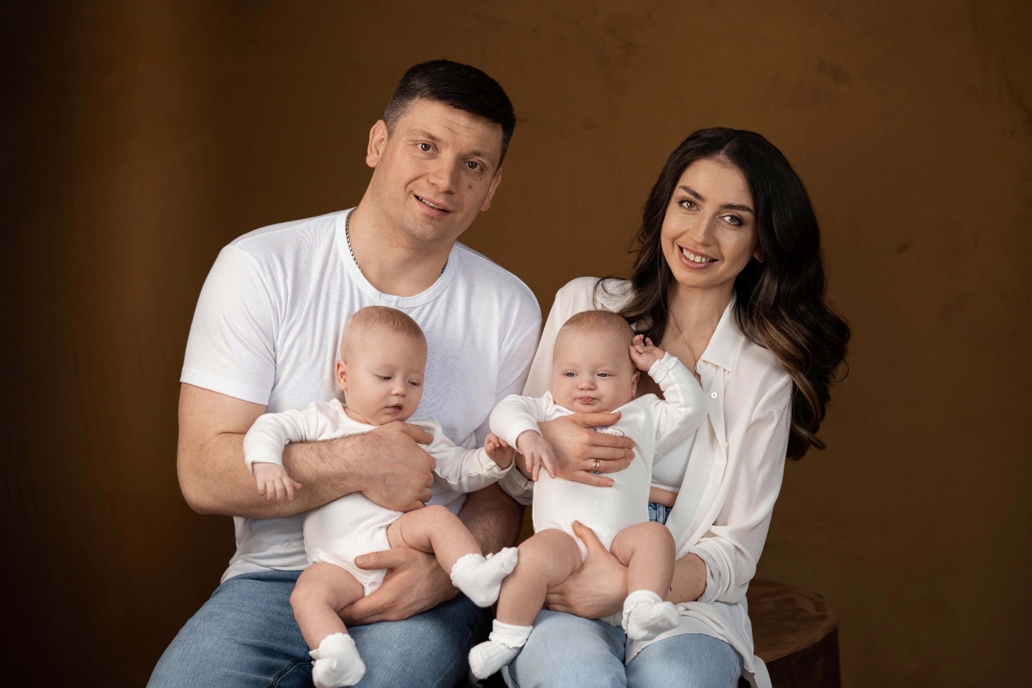 Батьки тримають на руках близнюків, даруючи тепло та ніжність