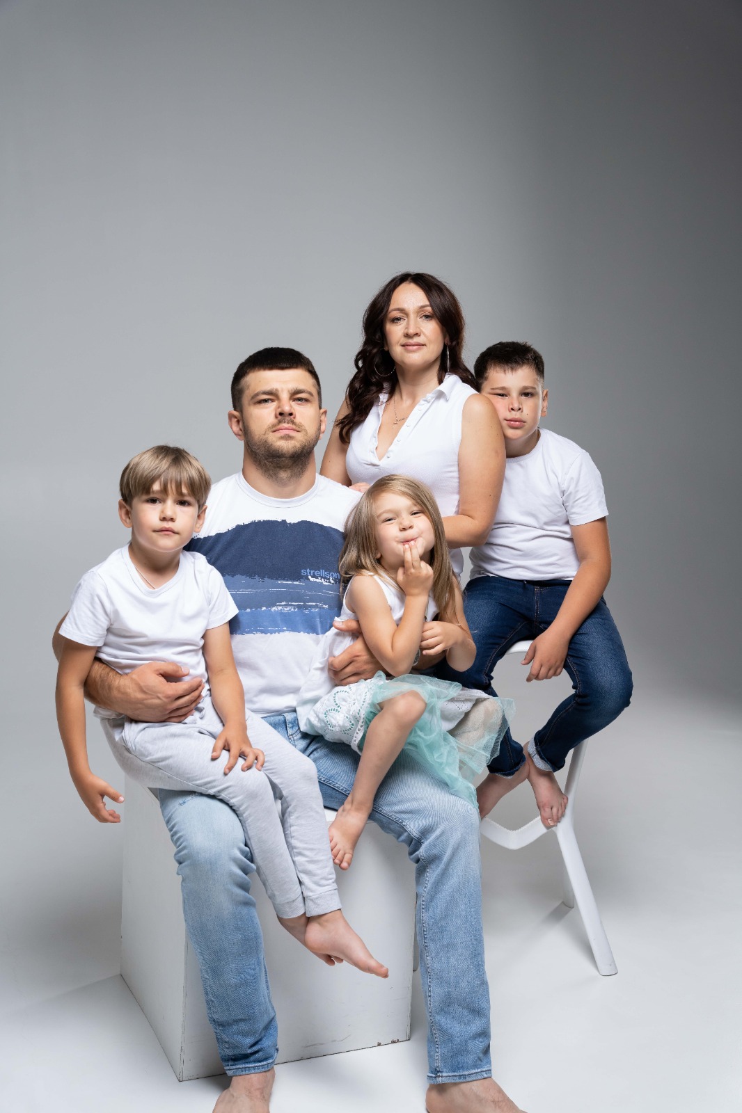 Тато з дітьми та мама позують у світлій фотостудії