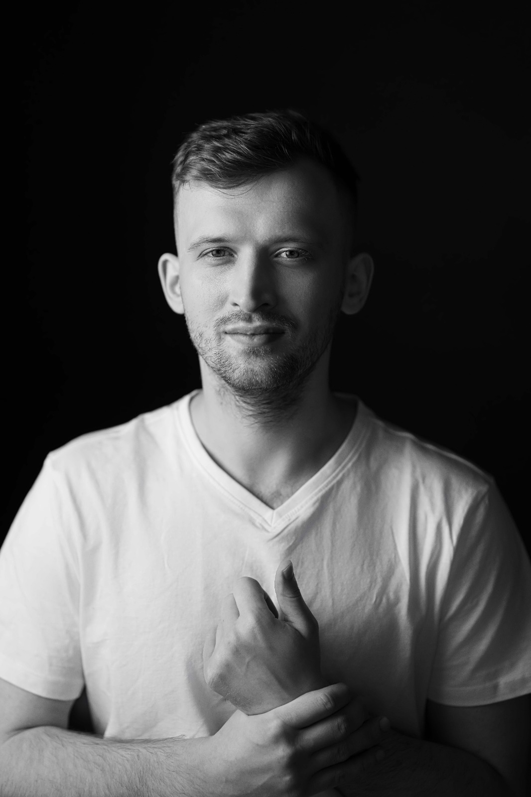 Чорно-білий чоловічий портрет у білій футболці на темному тлі