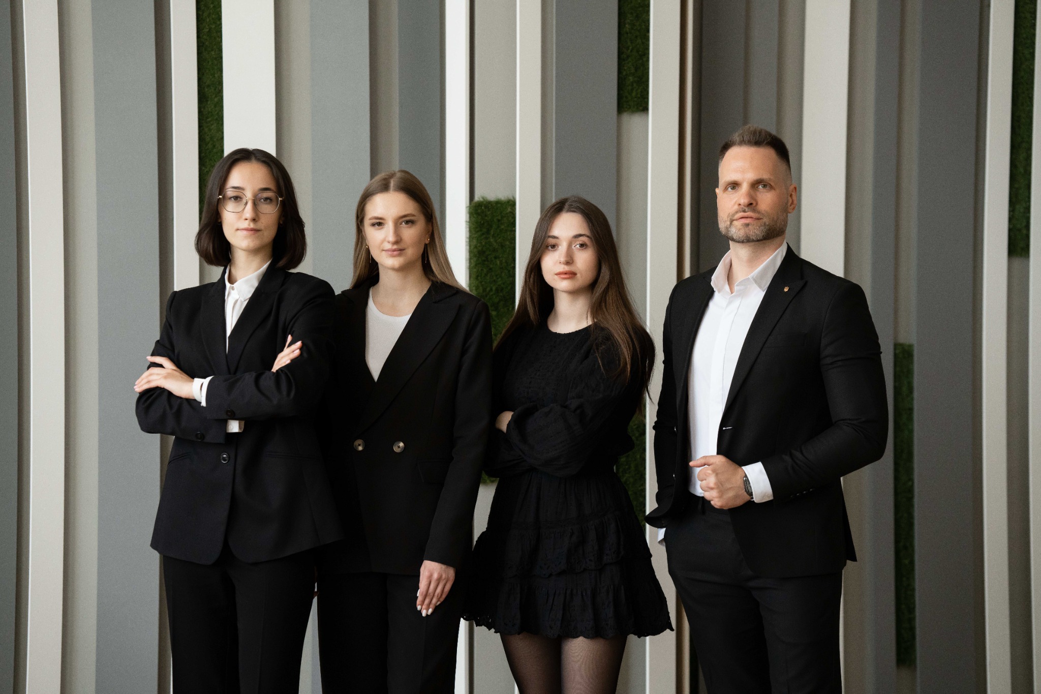 Команда спеціалістів у строгих костюмах біля сучасного світлого офісного інтер'єру